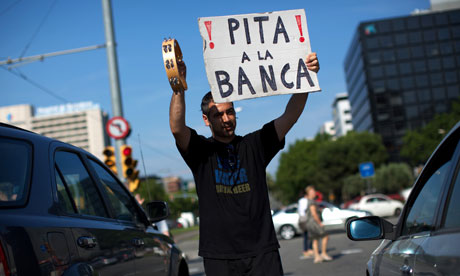 A demonstrator holds up a placard outside the La Caixa bank in Barcelona